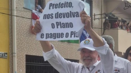 [Lula ergue cartaz em protesto contra gestão municipal durante cortejo do 2 de Julho]